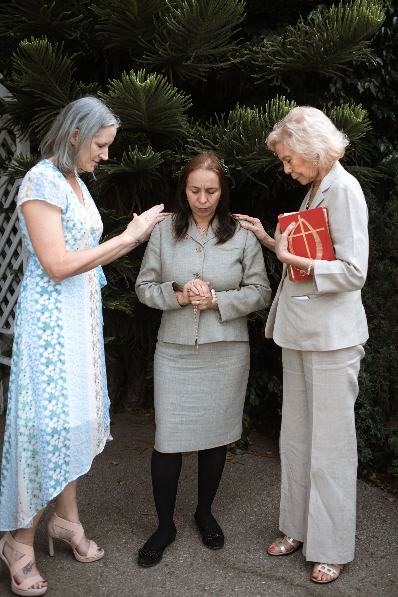Three Christian women praying together, one holding a Bible