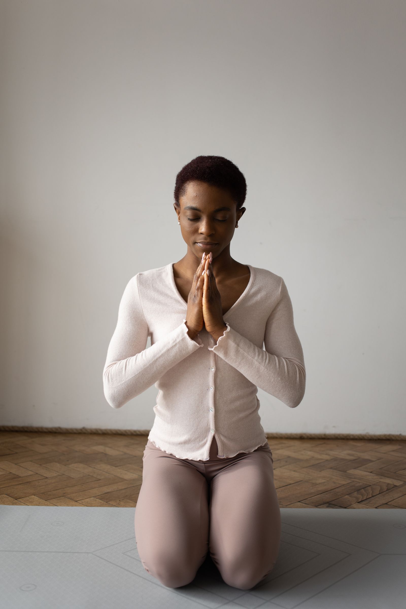 A woman sitting by a bright window with an open journal, pausing to pray